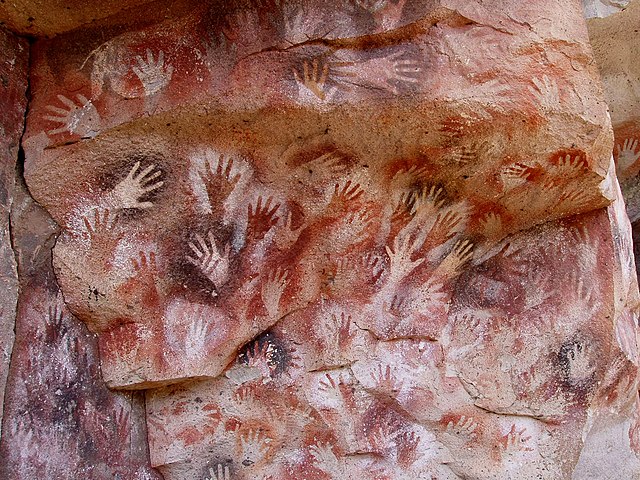 Cave painting with red paint outlining hands. 