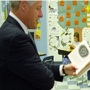 President Bill Clinton reading a book in a classroom