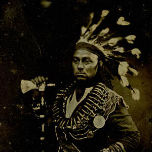 Maun-gua-daus (or Maun-gwa-daus), Chief of the Ojibwa Nation Thumbnail of a man in a native american headress holding a hatchet