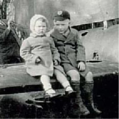 Detail of a photograph showing two children sitting on the wing of a crashed German fighter plane.